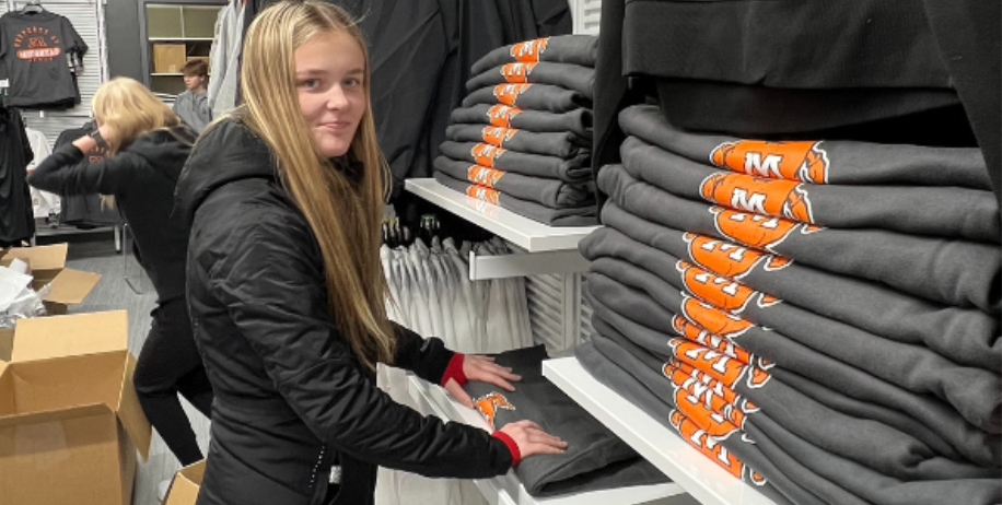 Student helps put away new merchandise