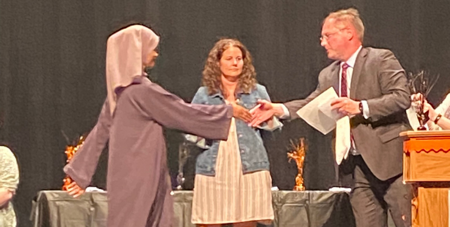 Superintendent Lunak hands student a graduation certificate