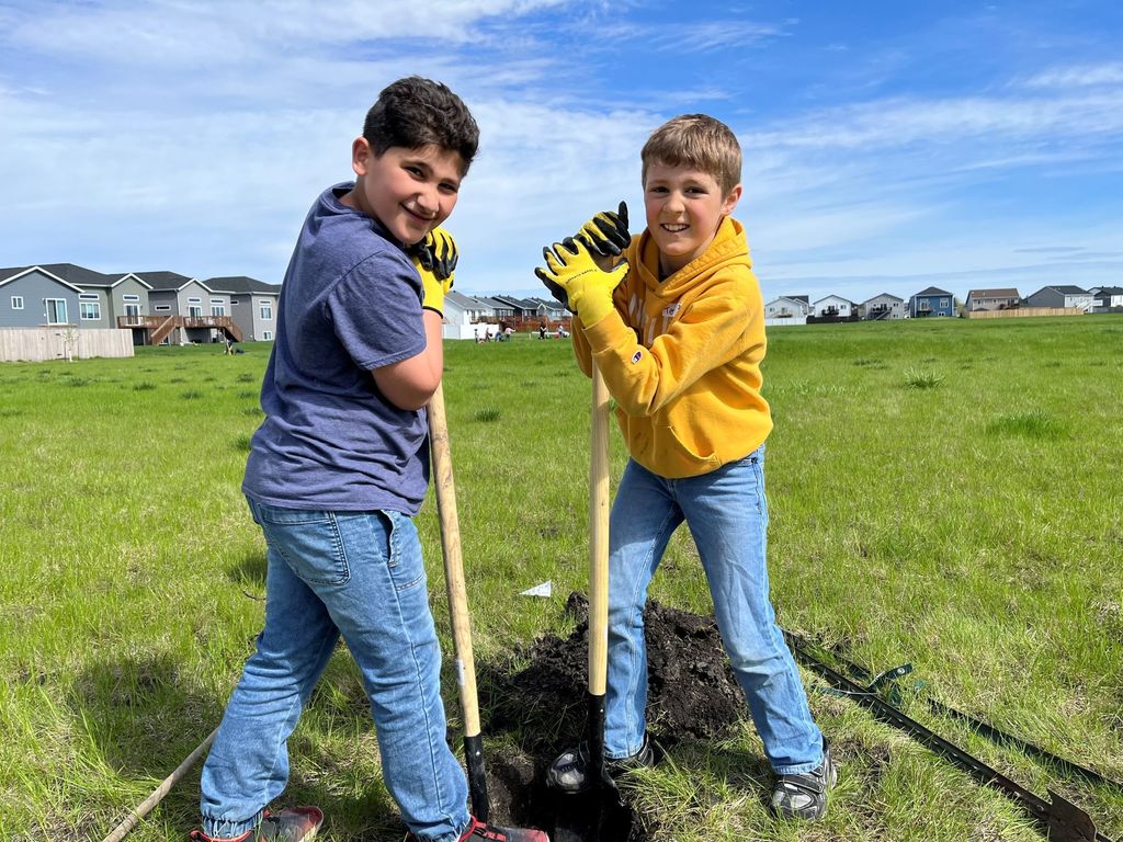 Two students dig a hole to plant a tree