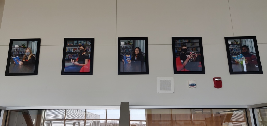 Pictures of students hang above the doorway in the library
