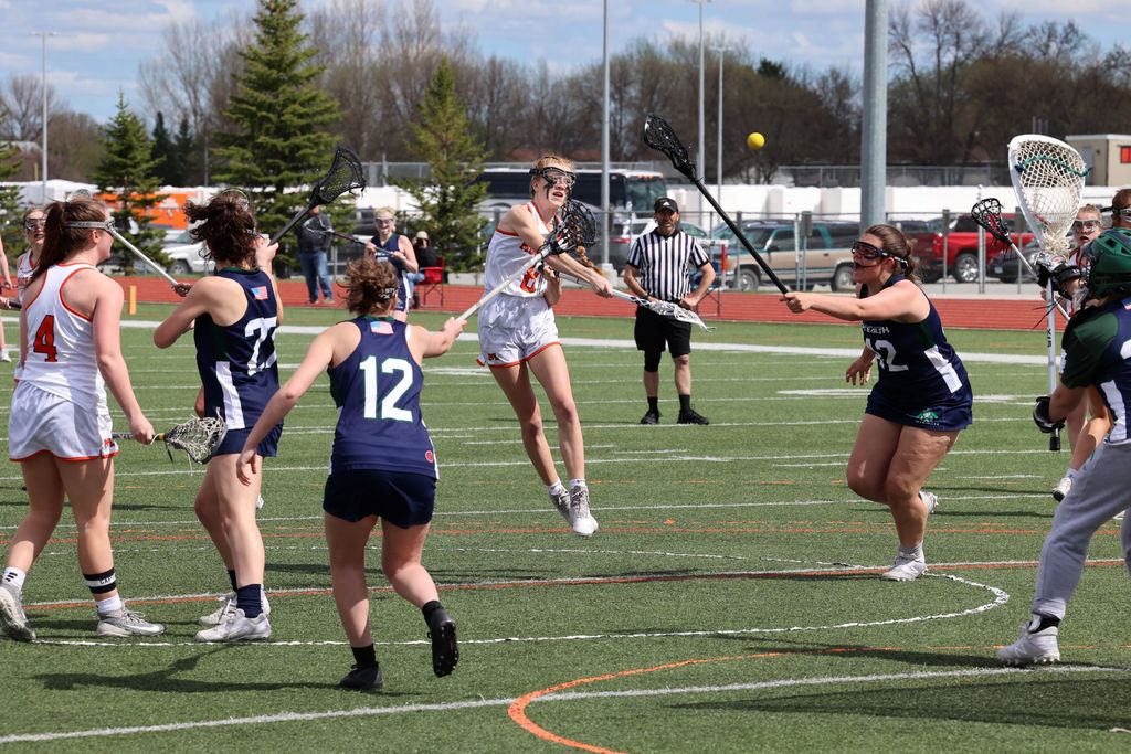 Girls lacrosse player throws the ball toward net