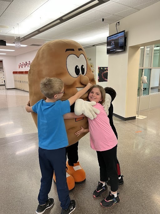 Spuddy mascot hugging students