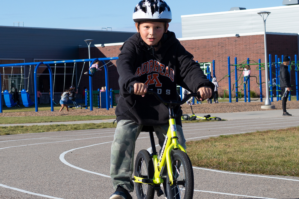 Student rides bike on elementary school track outside