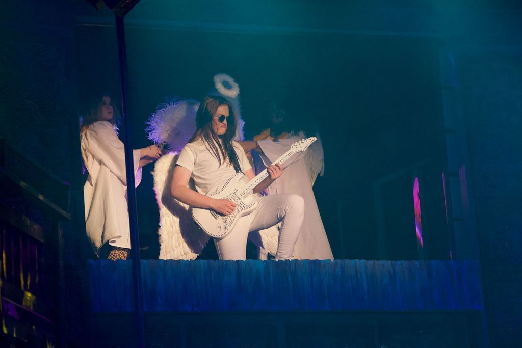 Student dressed in all white  and angel wings plays the guitar