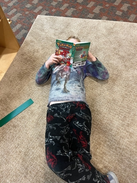 Stduent laying on the carpet reading a book