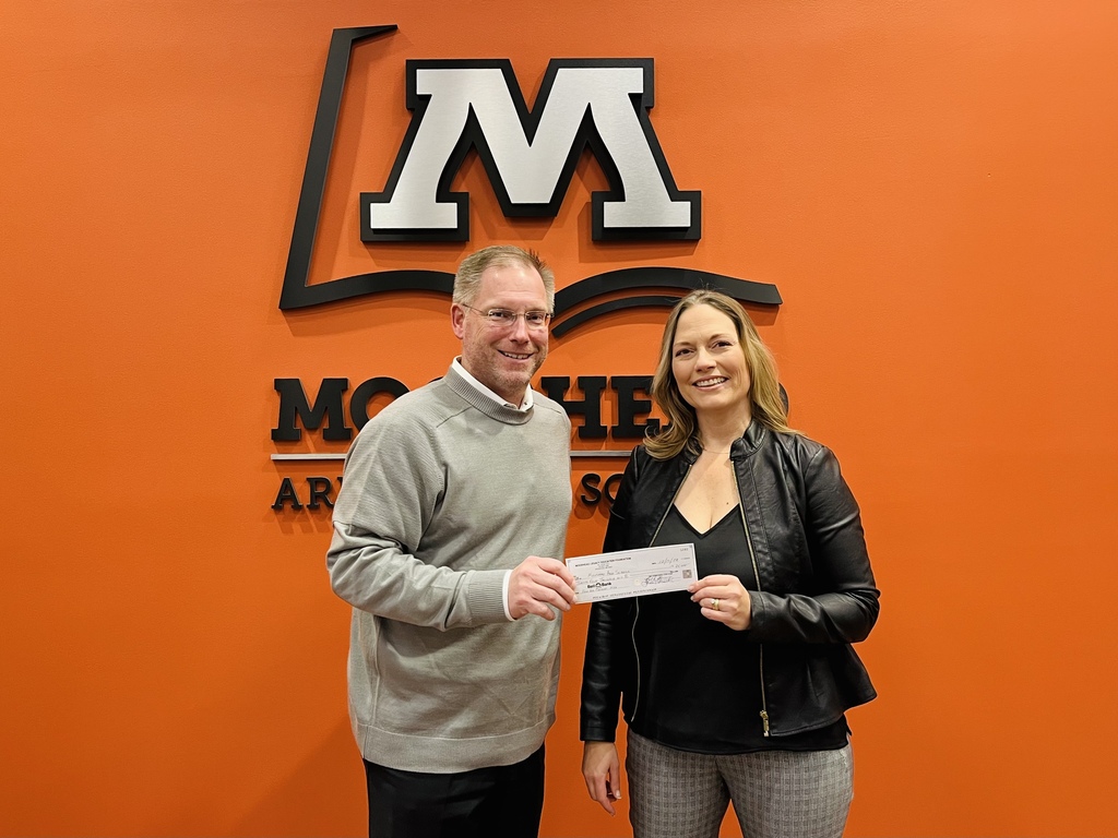 Janelle Leiseth from Moorhead Legacy hands Superintendent Brandon Lunak a check
