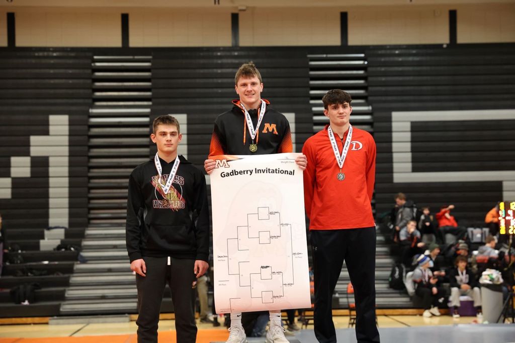 Student stands at the top of the podium at a wrestling meet