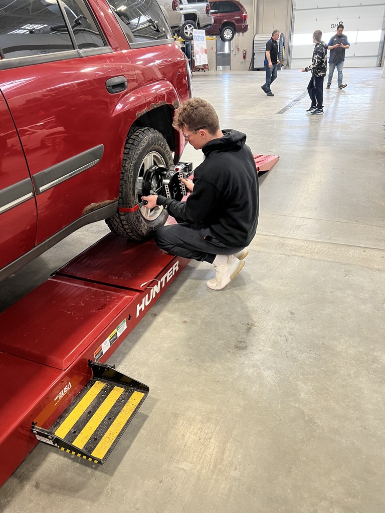 Student works on the tire of a car